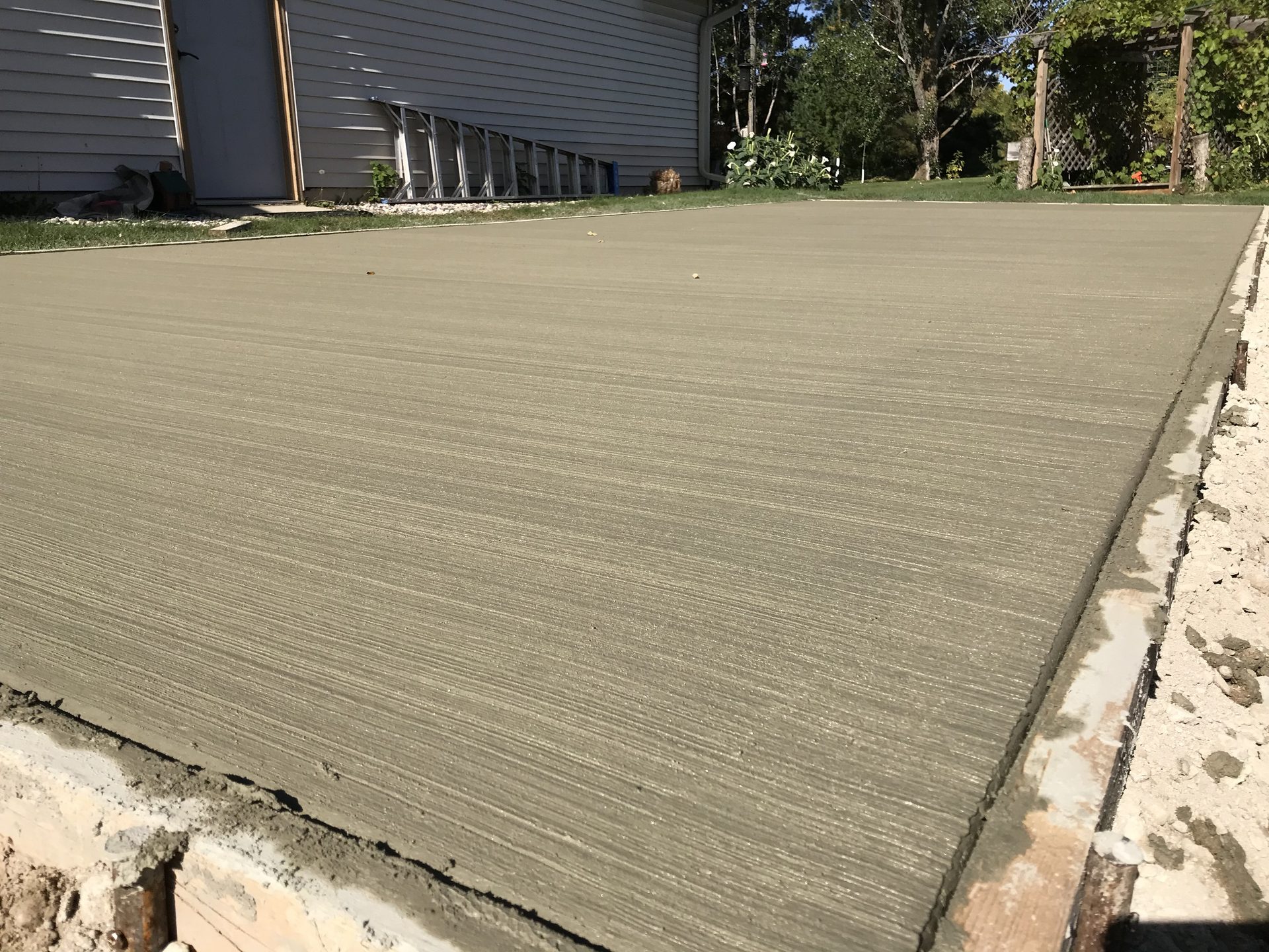 Newly finished concrete driveway with smooth broom finish surface and concrete edging.
