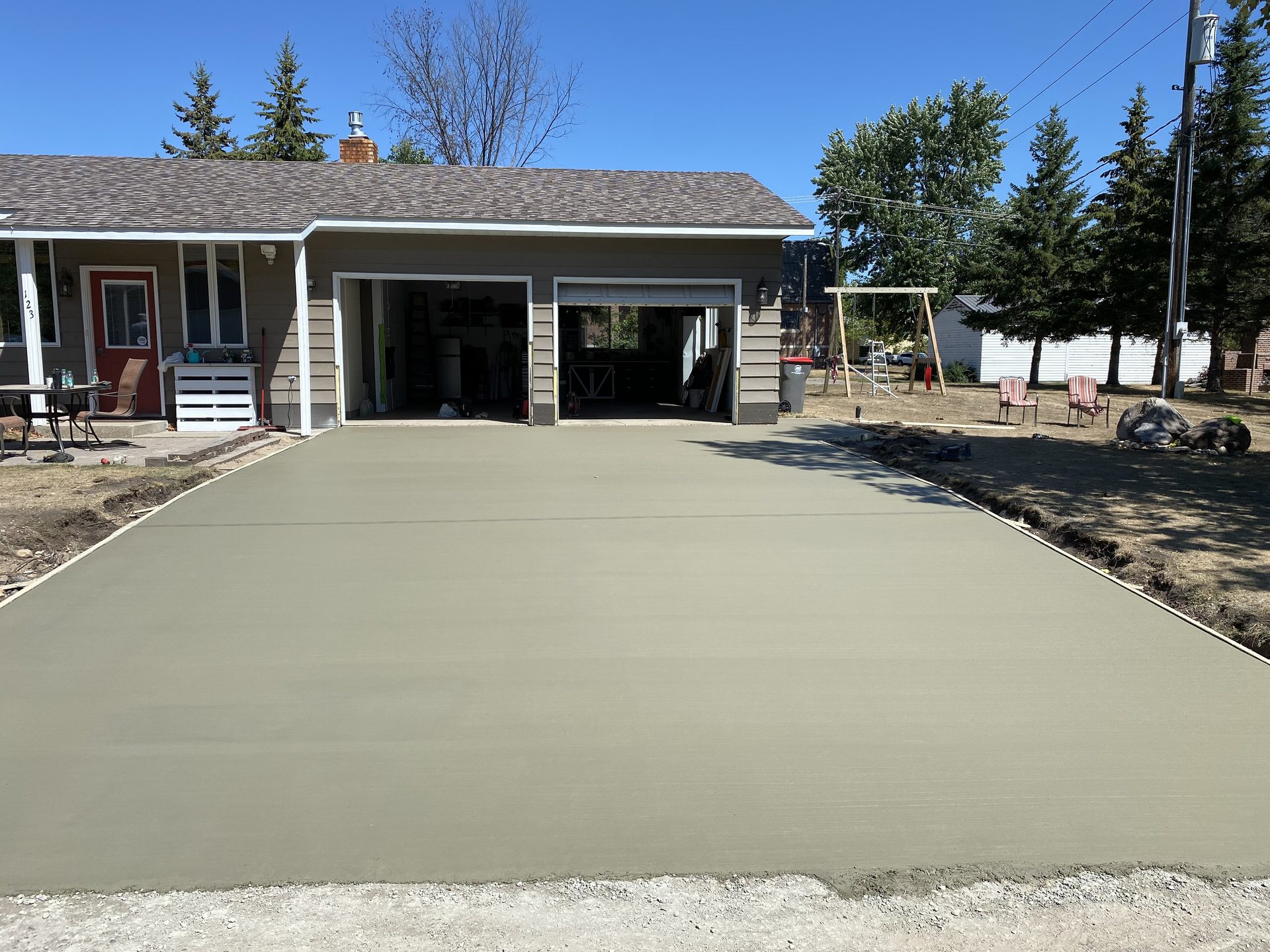 Newly poured concrete driveway extending from a two-car garage with freshly finished gray concrete surface.