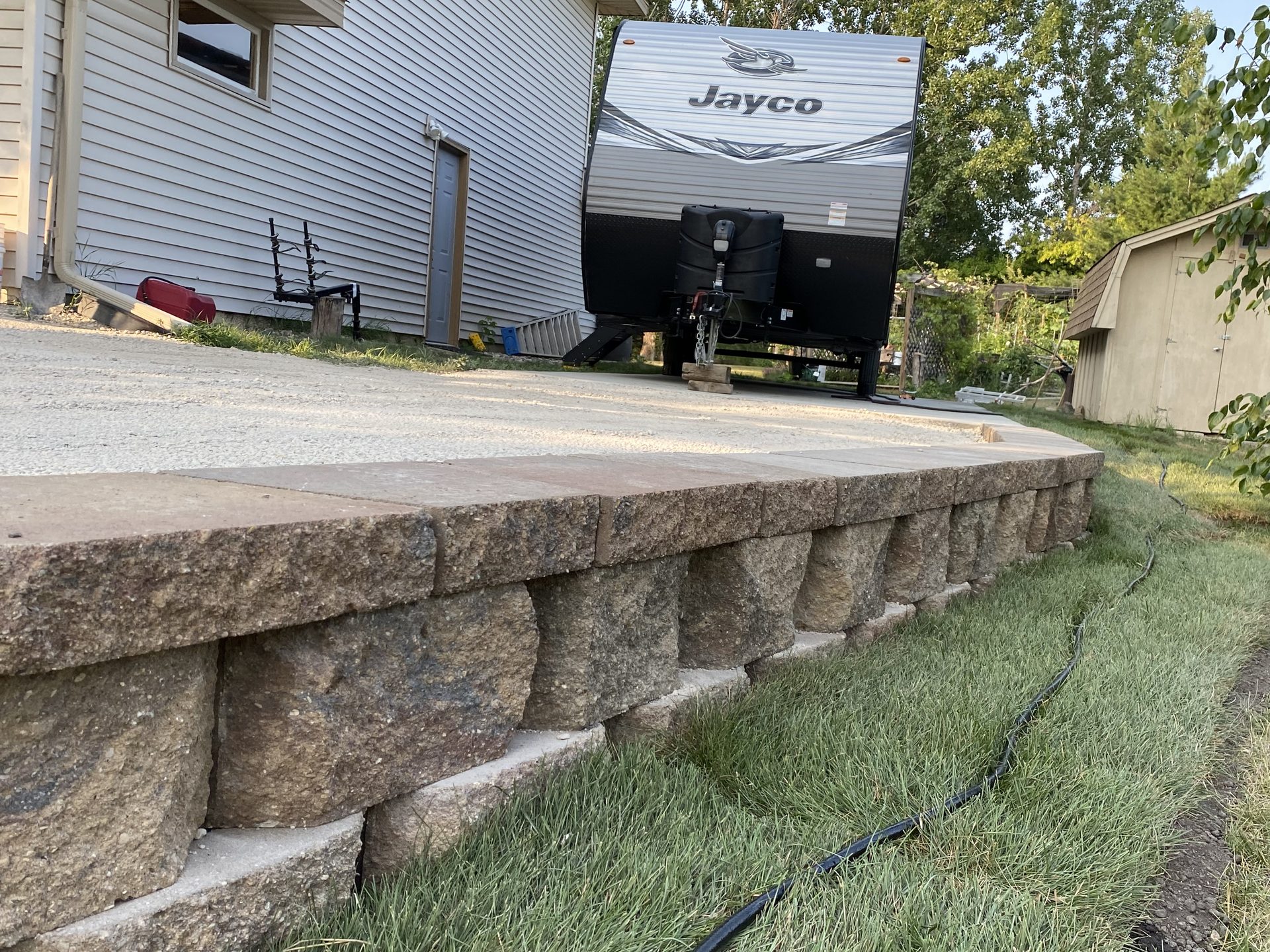 Completed concrete retaining wall with finished cap and proper grading, showing landscape construction work.