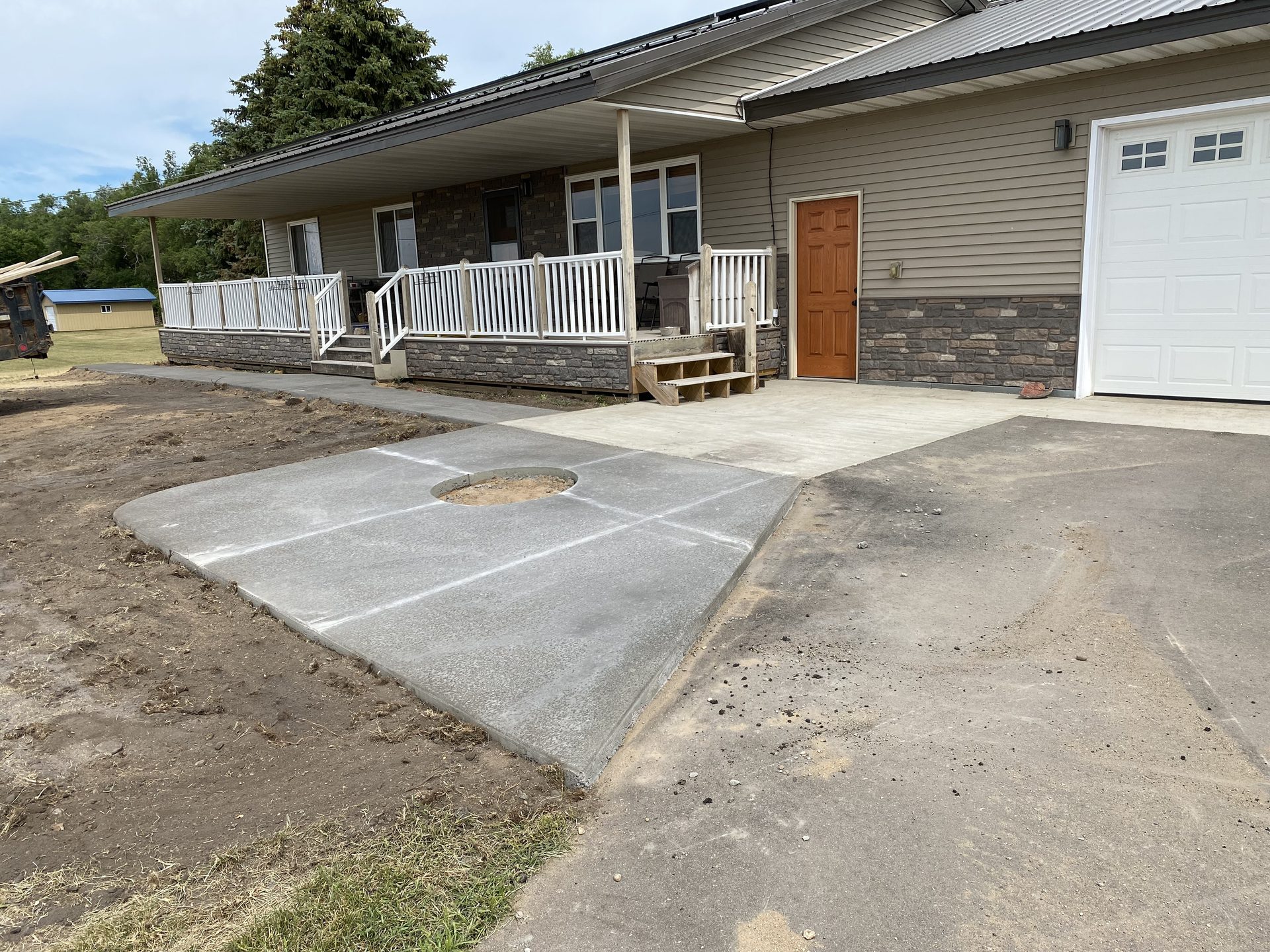 New concrete driveway with geometric scoring pattern installed in front of residential home with stone veneer foundation and attached garage.