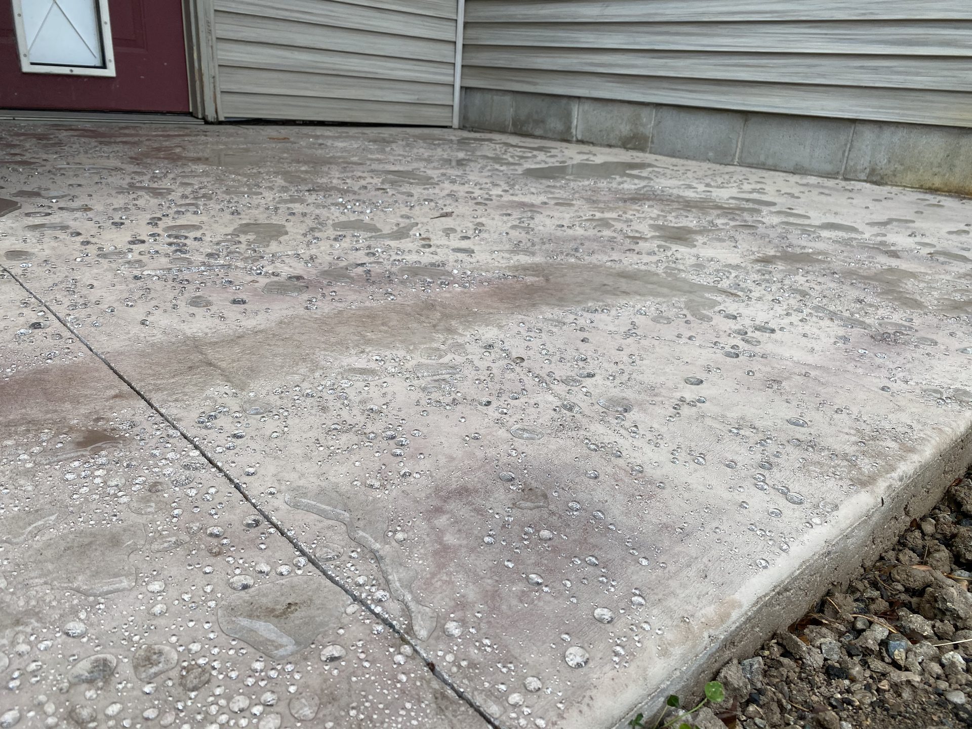 Finished concrete patio with control joints and decorative aggregate, adjacent to residential garage.