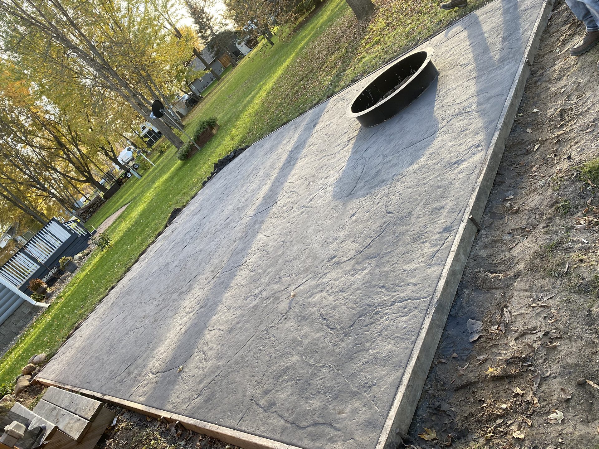 Finished concrete patio with smooth gray surface and white concrete border, taken from elevated angle.