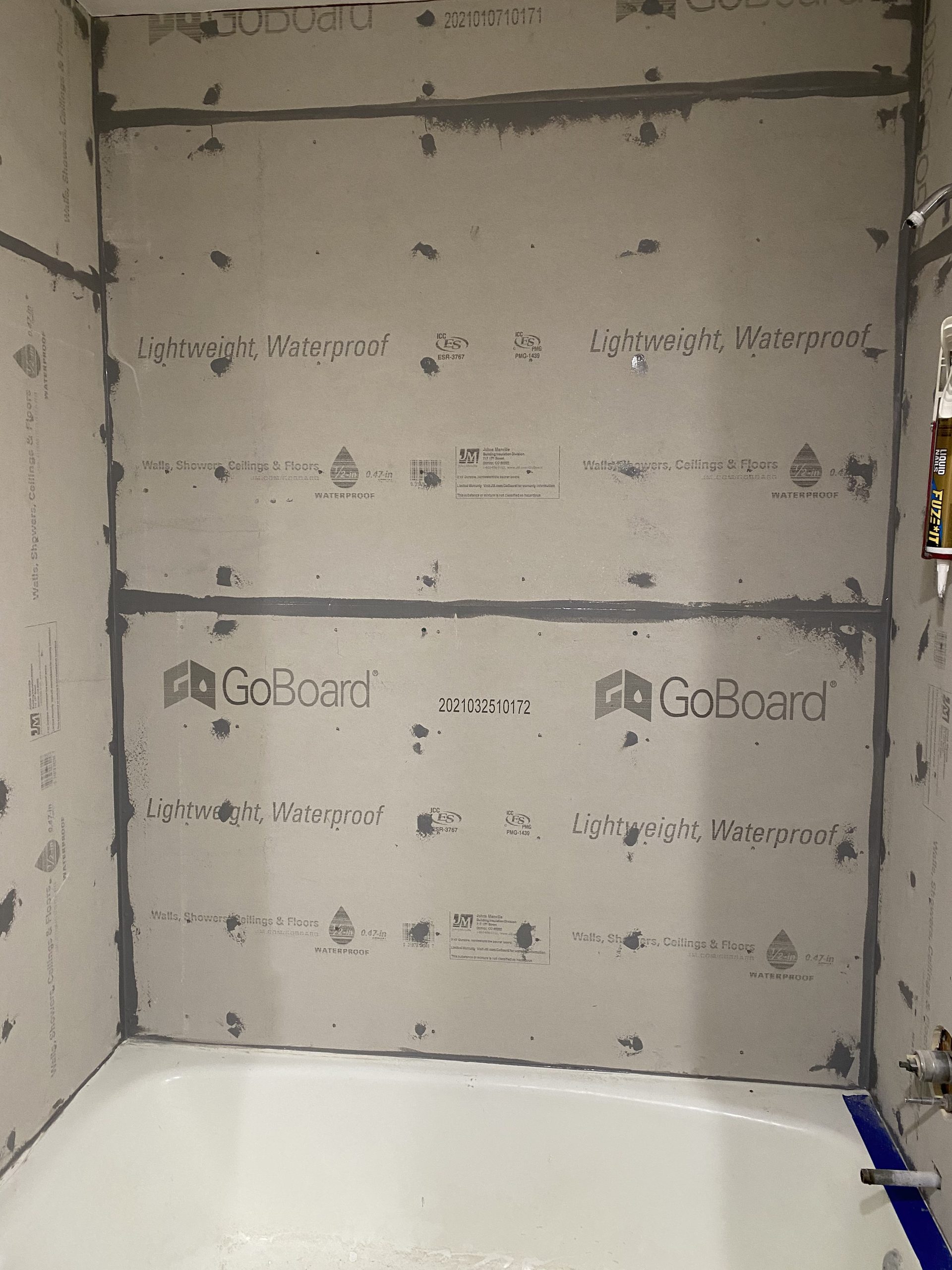 Bathroom shower waterproofing board installation showing GoBoard lightweight waterproof panels with sealing tape and fasteners in progress.