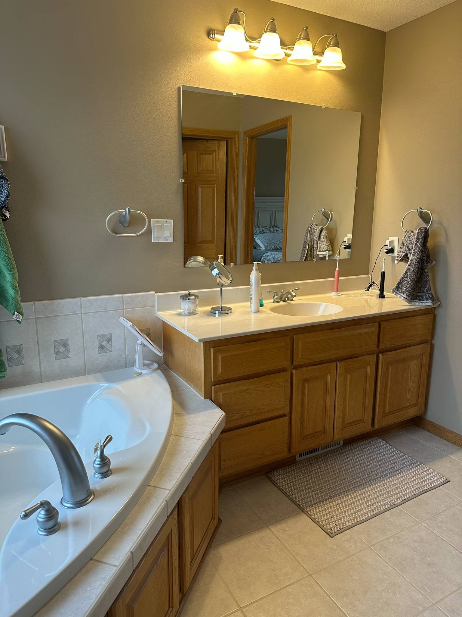 Master bathroom double vanity with wood cabinetry, granite countertop, and framed mirror with overhead lighting